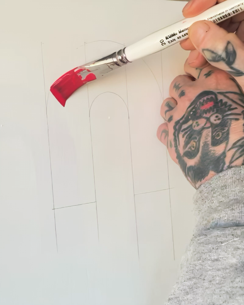 Close up of hands painting on white background with red paint 