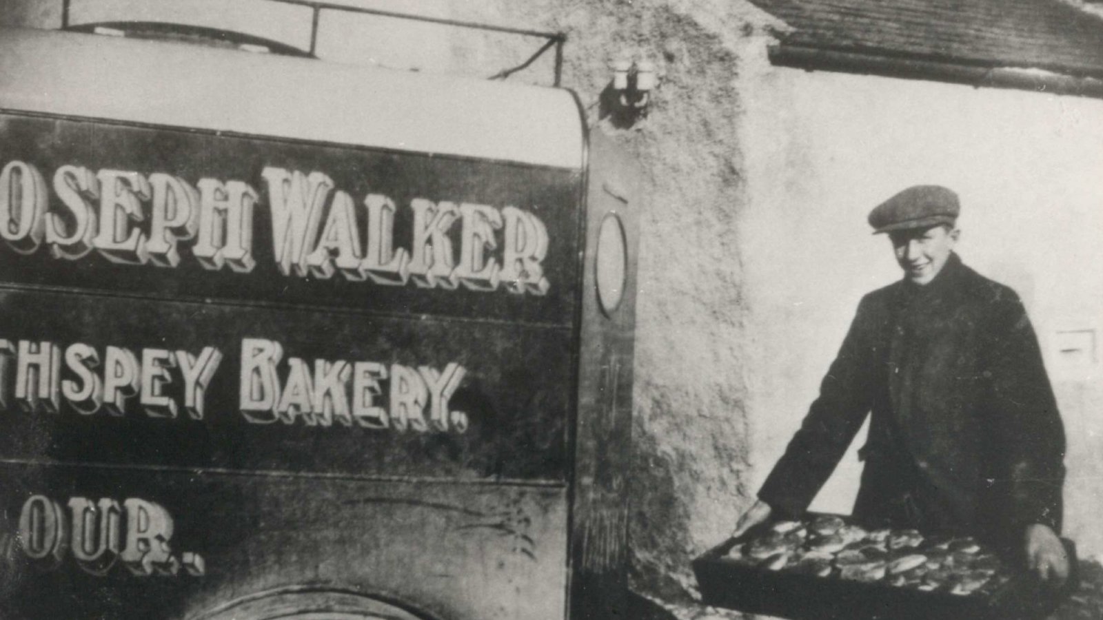 a vintage photo of Walkers shortbread van in black and white with man carrying a tray of goods